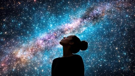 Woman stands silhouette against vibrant galaxy filled with stars and cosmic colors